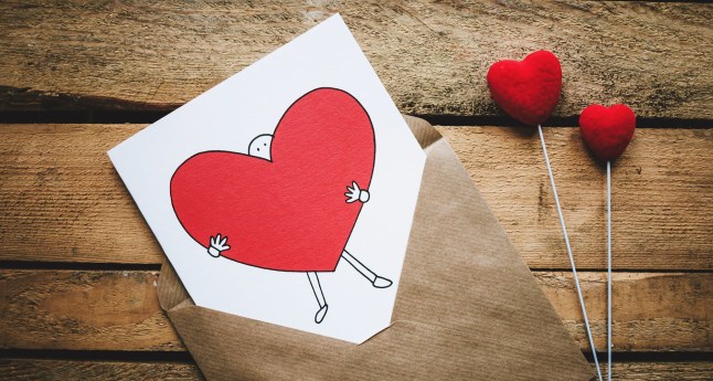 white black and red person carrying heart illustration in brown envelope